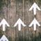 white arrows pointing upwards on a wooden board