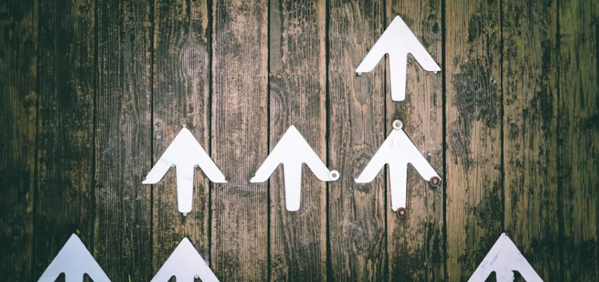 white arrows pointing upwards on a wooden board