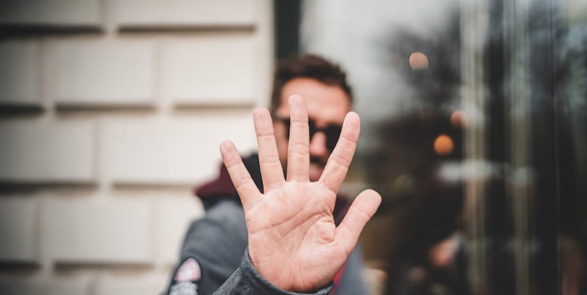 Man handing his hand up showing all five fingers/thumb